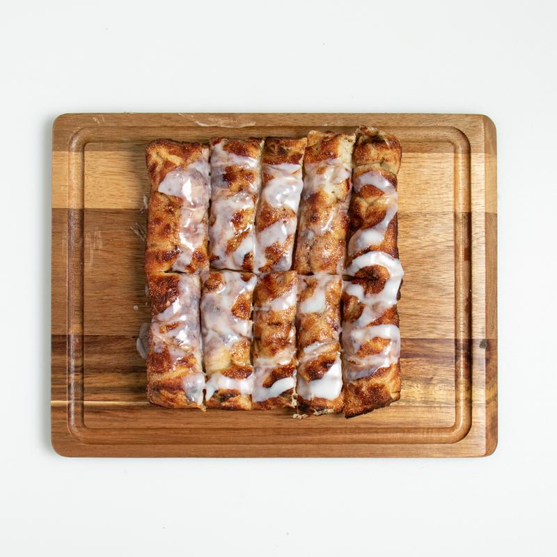 DPC Cinnamon Pan dessert with icing drizzle on a wood board