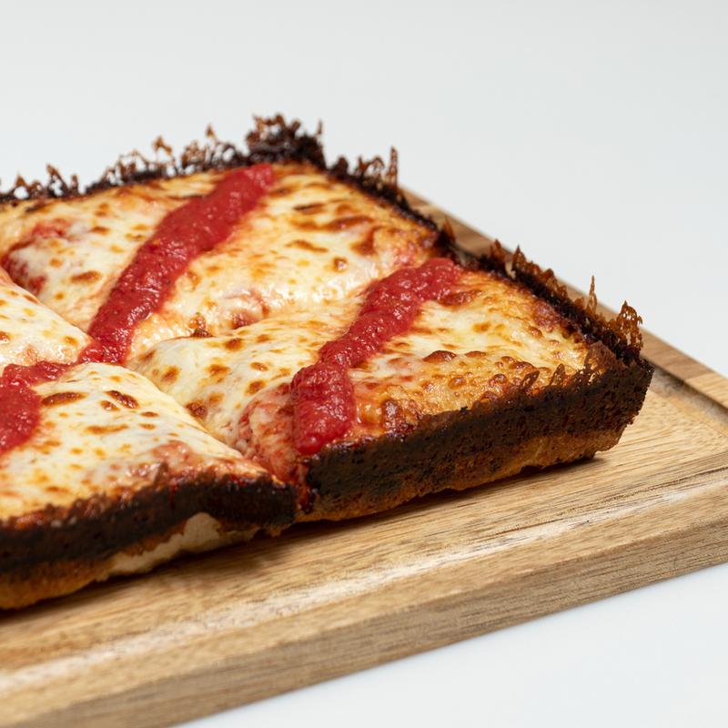 Crispy caramelized corner of a Detroit-style cheese pizza